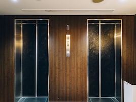 Dos puertas de ascensor con un revestimiento de pared de madera y un cartel que indica el número de piso.