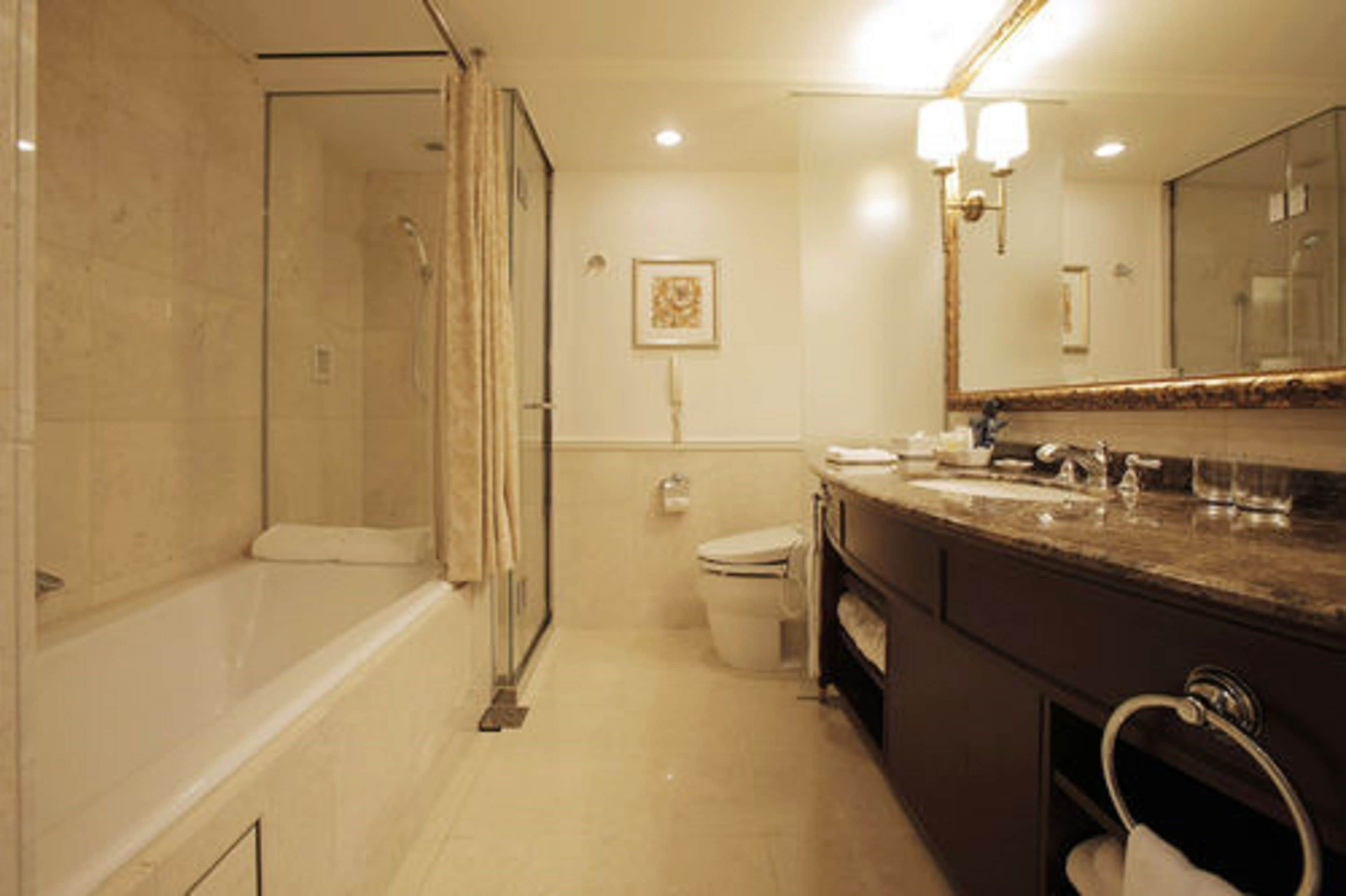 A bathroom with a bathtub, toilet, and vanity with a mirror.