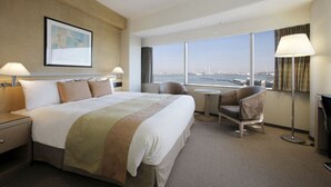 Une chambre d’hôtel avec un grand lit, un bureau, une chaise et une vue sur le paysage urbain.