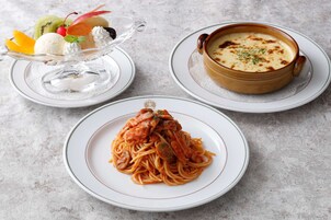 Un plato de espagueti con salsa de tomate, un tazón de sopa y un postre con helado y fruta.