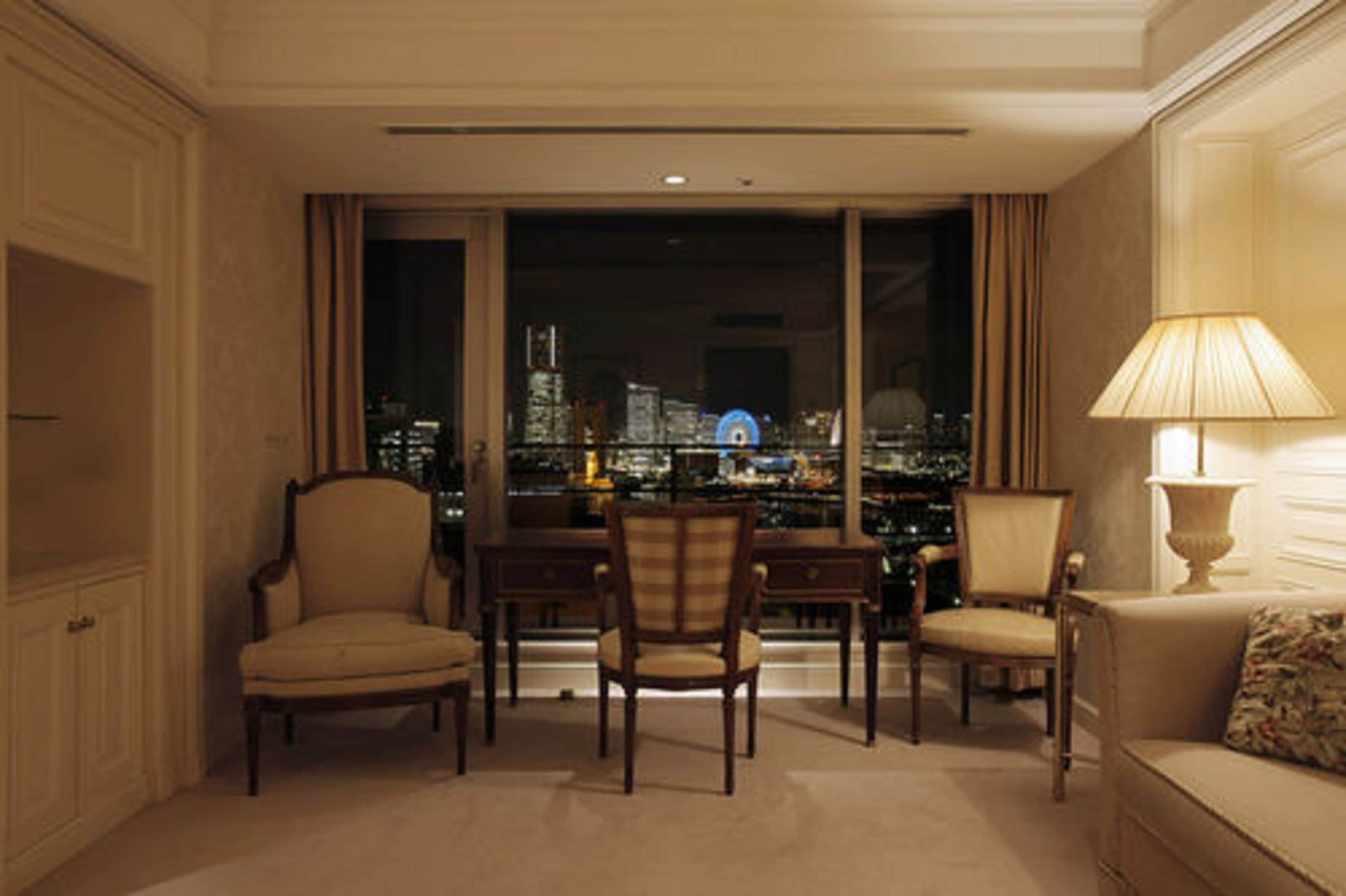 Une pièce avec vue sur la ville, comprenant un canapé, deux fauteuils, une table et une lampe.