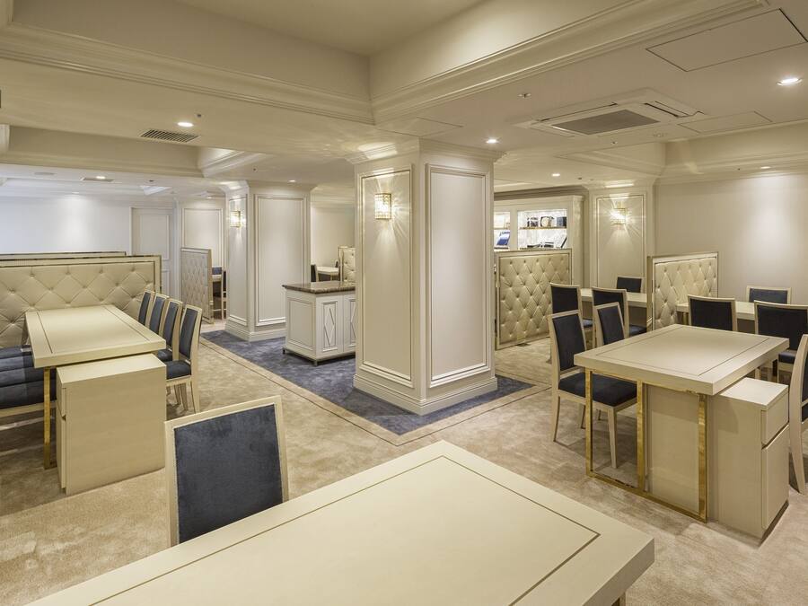 Un vestíbulo de hotel con una zona de estar central, un mostrador de recepción y un bar.