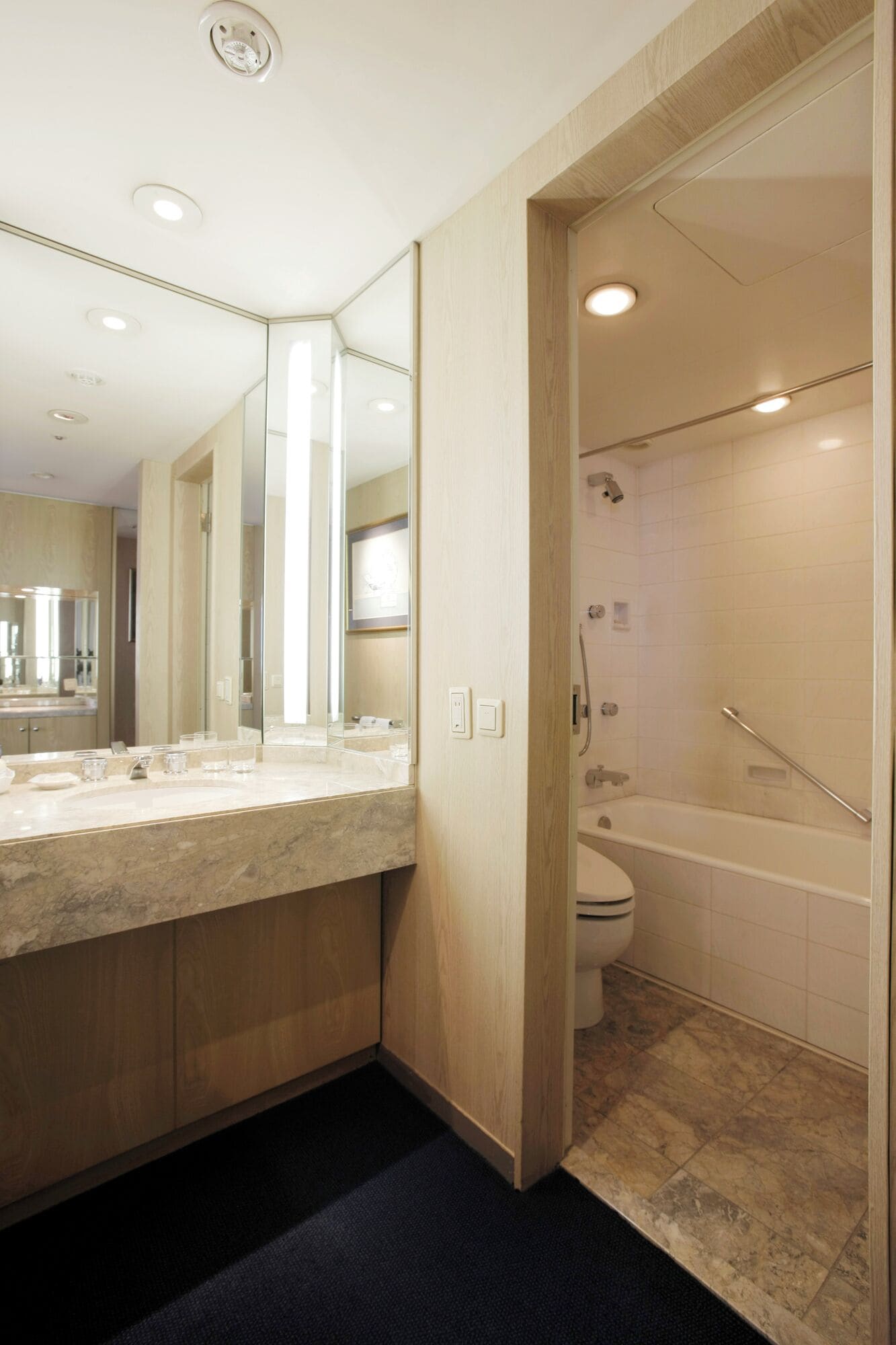 A modern bathroom with a marble sink, a large mirror, and a separate shower area.