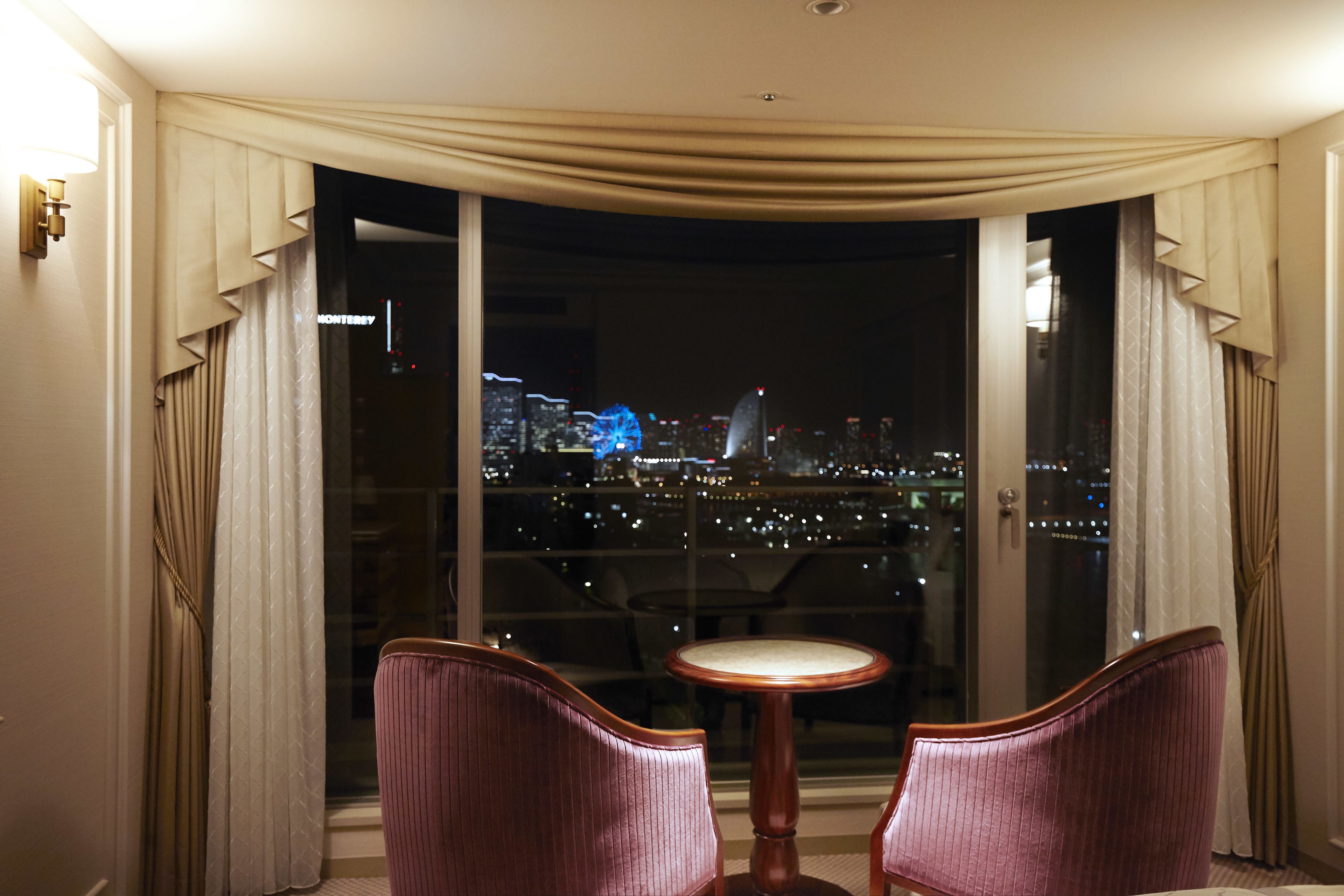 A room with a large window, two chairs, and a small table.