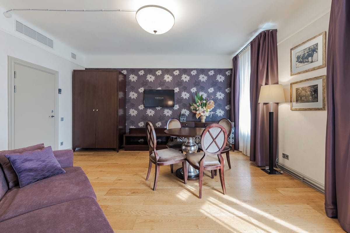 A modern living room with a sofa, a dining table with chairs, a TV, and a decorative vase.