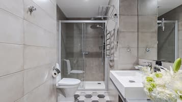 Uma casa de banho moderna com chuveiro, sanita e lavatório.