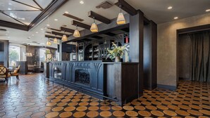 Zona de bar con piso estampado, una barra con un jarrón de flores e iluminación colgante.