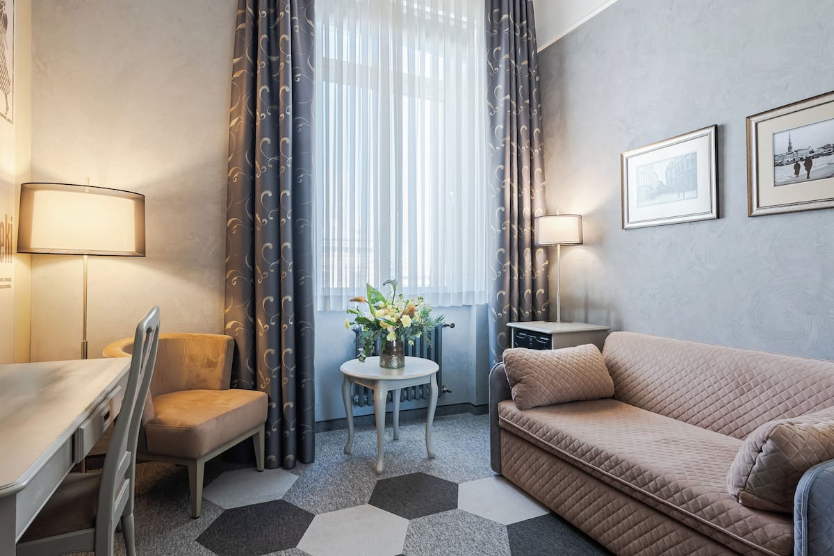 A compact living space with a sofa, a chair, a small table with a vase, and a lamp.