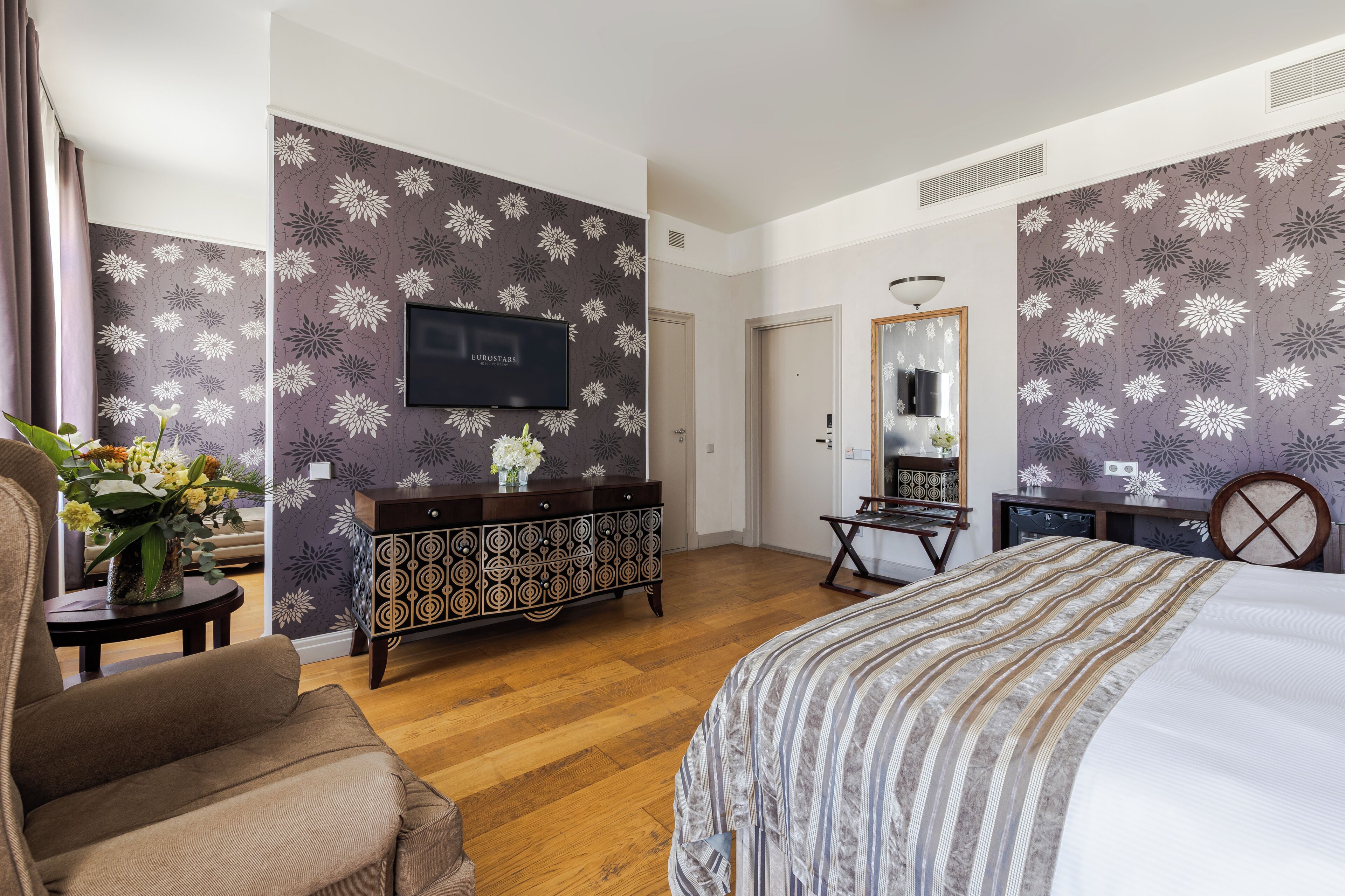 A hotel room with a bed, a TV, a dresser, and a mirror.