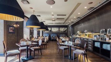 Een restaurant met houten tafels en stoelen, een toonbank met etenswaren en een modern plafondontwerp.
