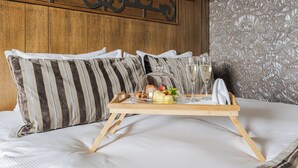 Una cama bien tendida con almohadas a rayas, una bandeja de madera con alimentos para el desayuno y un adorno decorativo en la pared.