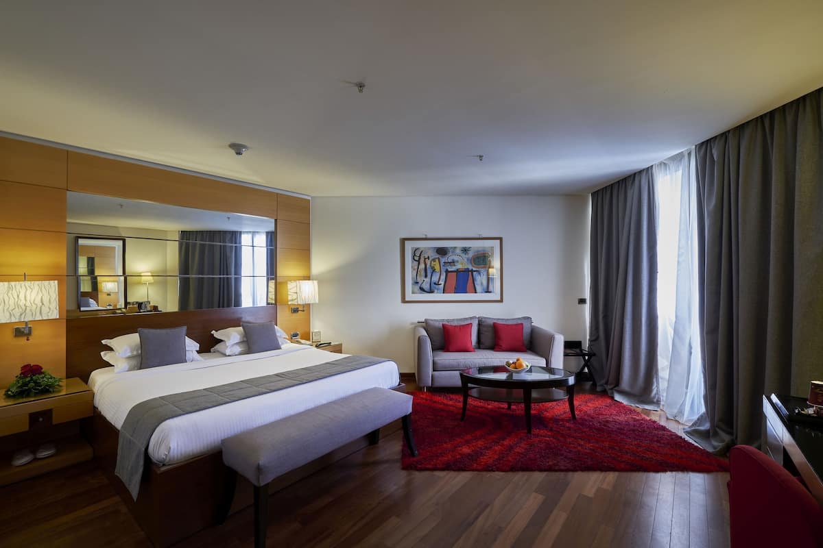 Une chambre d’hôtel avec un grand lit, un canapé, une table basse et un tableau au mur.