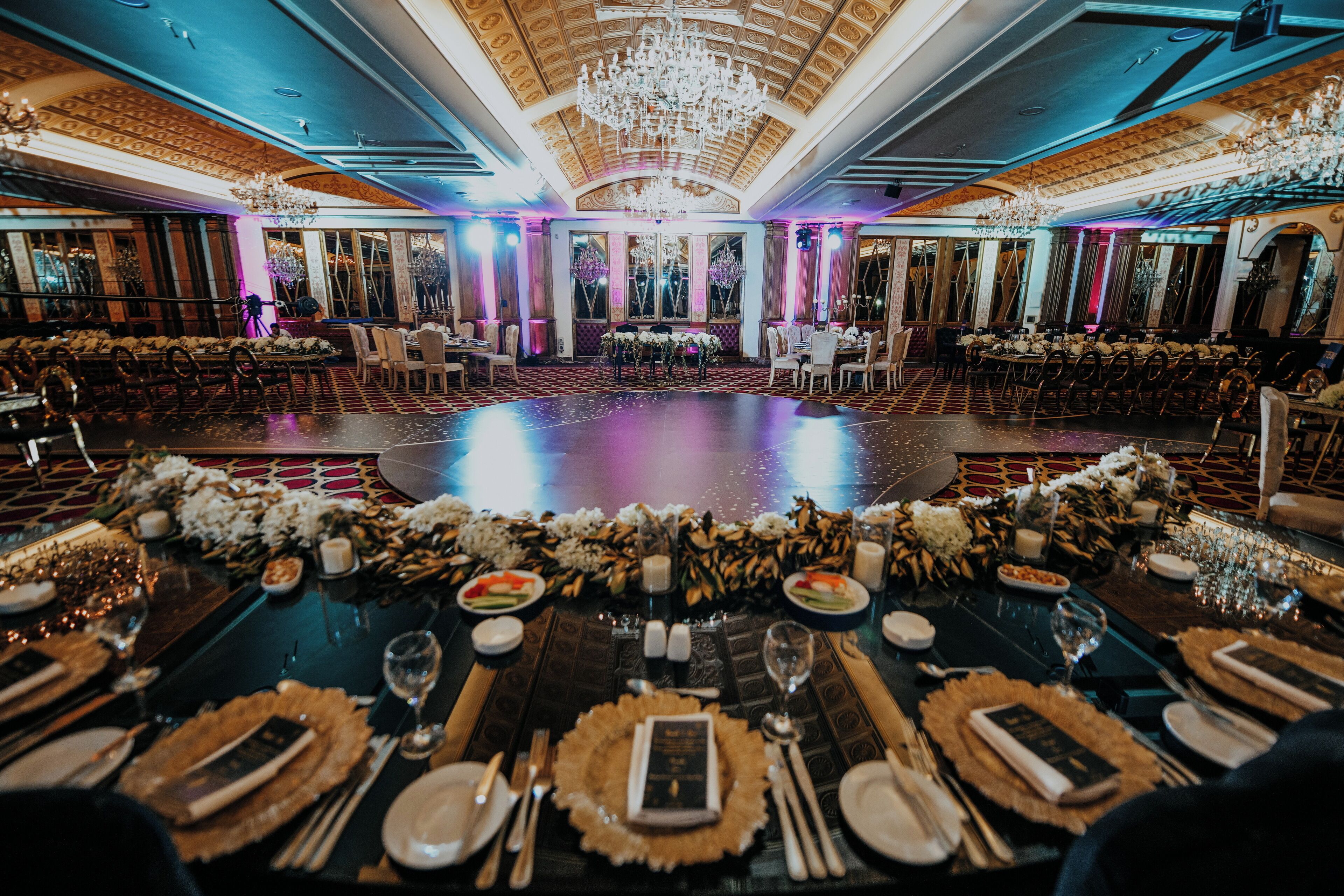 Un salón de banquetes con mesas redondas, candelabros y centros de mesa florales.