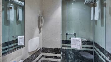 Un baño moderno con ducha de vidrio, un lavabo blanco y suelo de mármol.