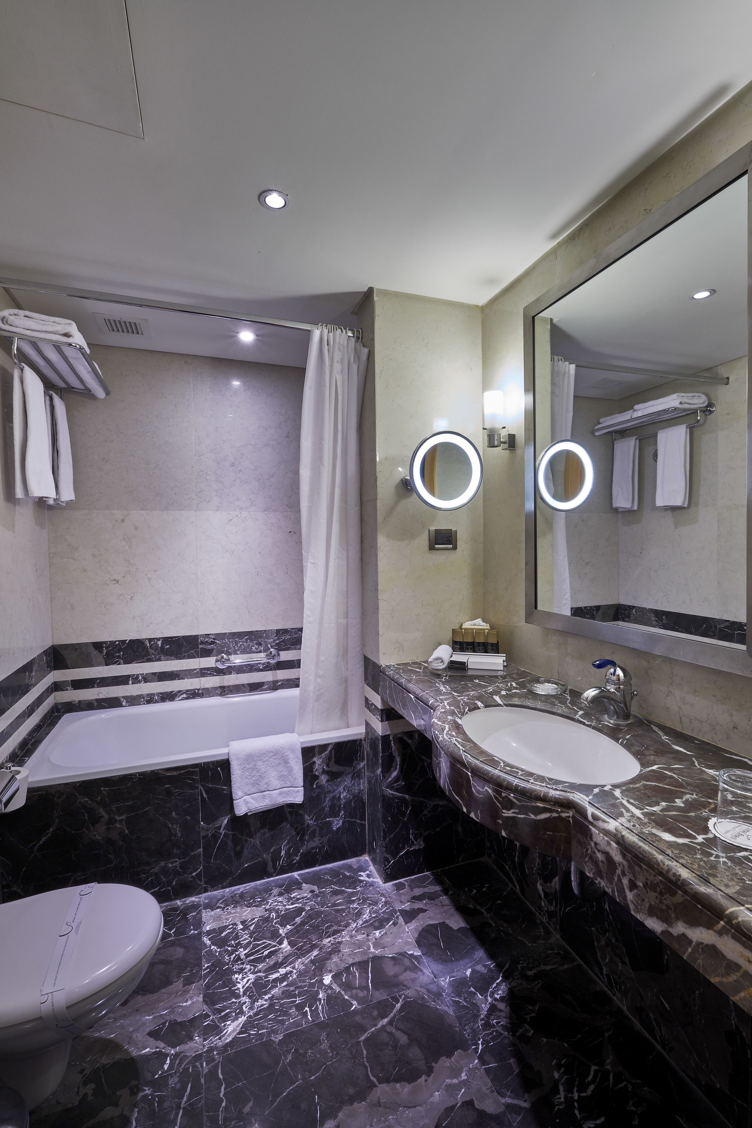 A modern bathroom with a bathtub, two sinks, and a toilet.