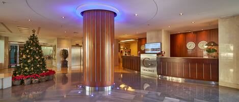 A modern lobby with a large cylindrical column, a reception desk, and a Christmas tree.