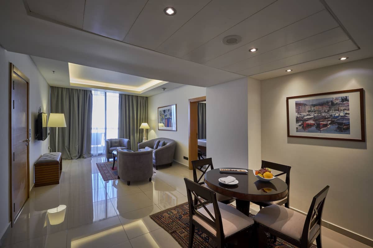 Une chambre d’hôtel moderne avec un coin repas, un canapé, une télévision et un tableau au mur.