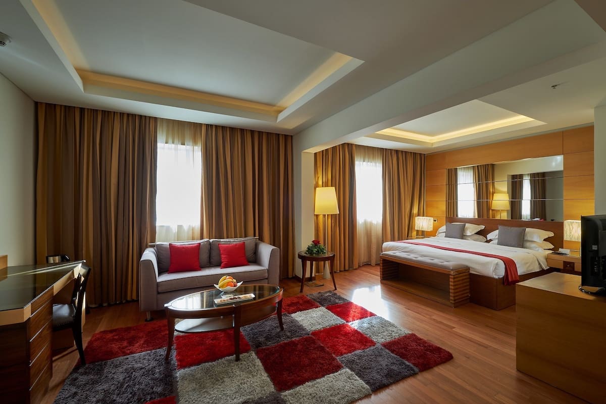 Une chambre d’hôtel avec un canapé, un lit, un bureau et une télévision.