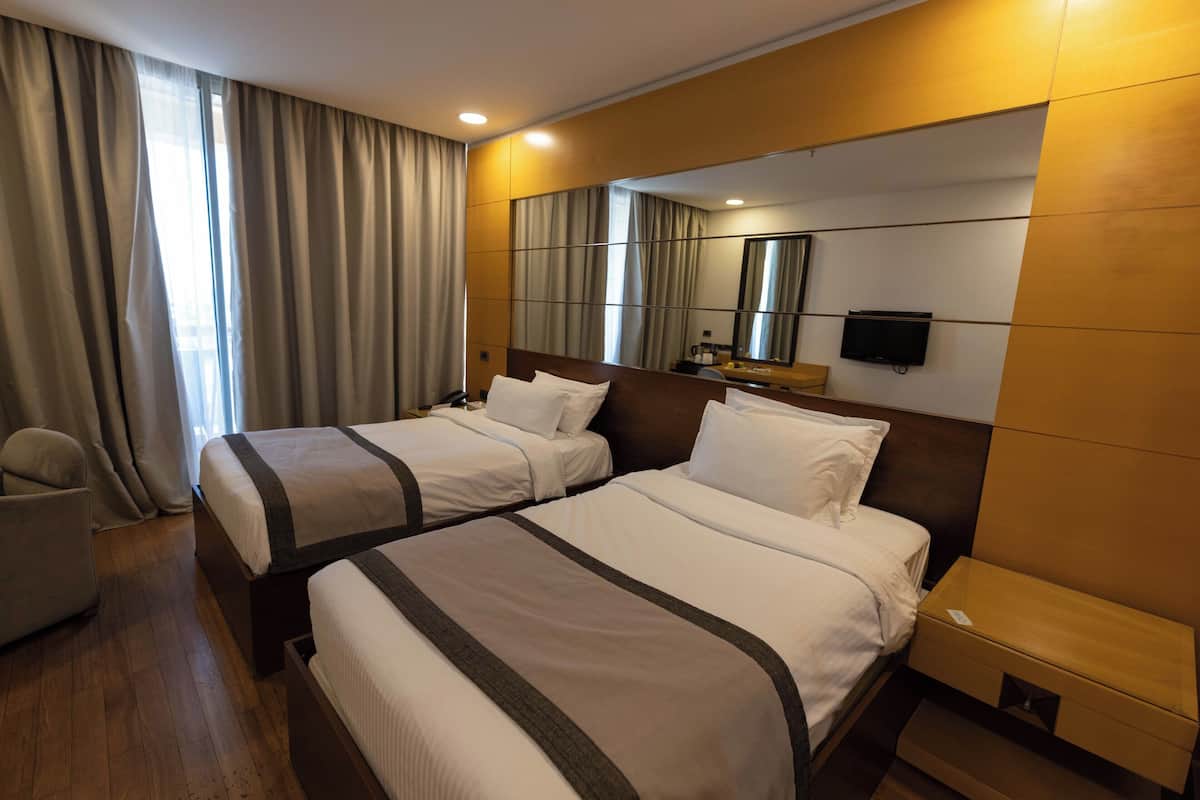 Une chambre d’hôtel avec deux lits, une télévision, un bureau et une chaise.