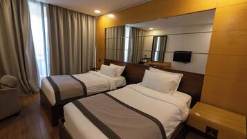Een hotelkamer met twee bedden, een televisie, een bureau en een stoel.