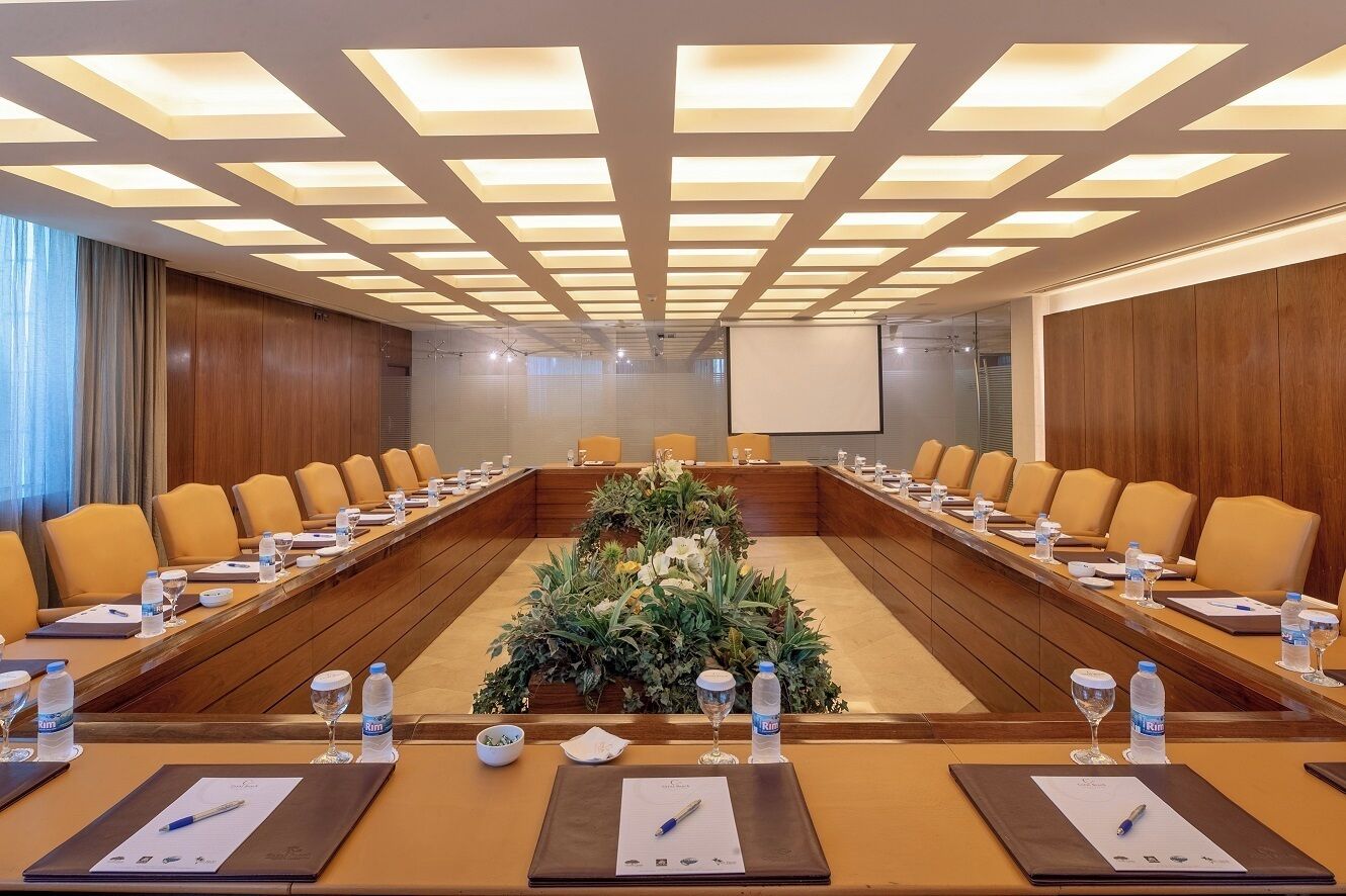 Une salle de conférence équipée d’une longue table, de nombreuses chaises et d’un écran de projection.