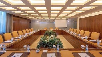 Une salle de conférence équipée d’une longue table, de nombreuses chaises et d’un écran de projection.