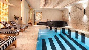Un área de spa con piscina, sillas de descanso y un muro de piedra.