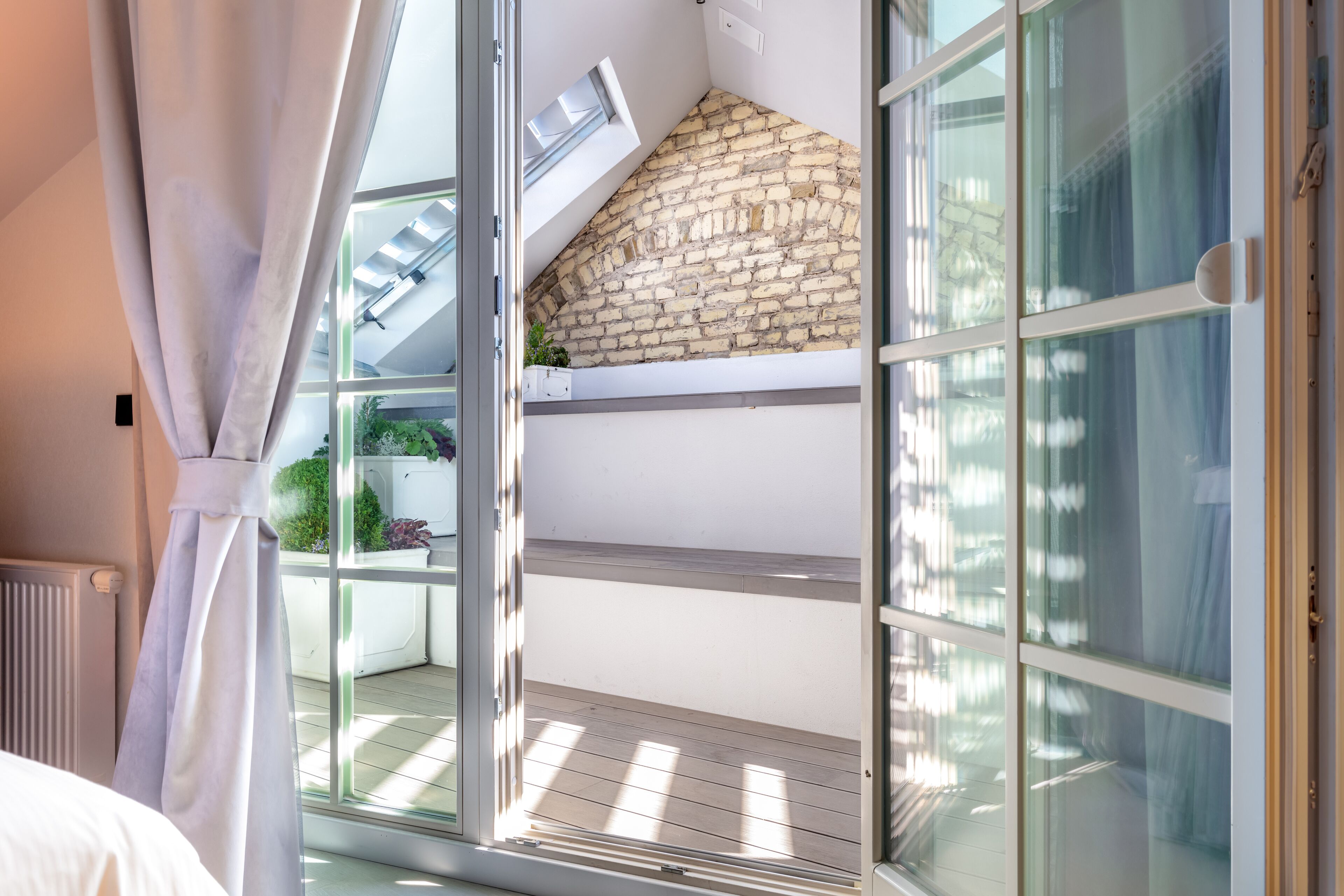 A balcony with a stone wall, a window, and a plant.