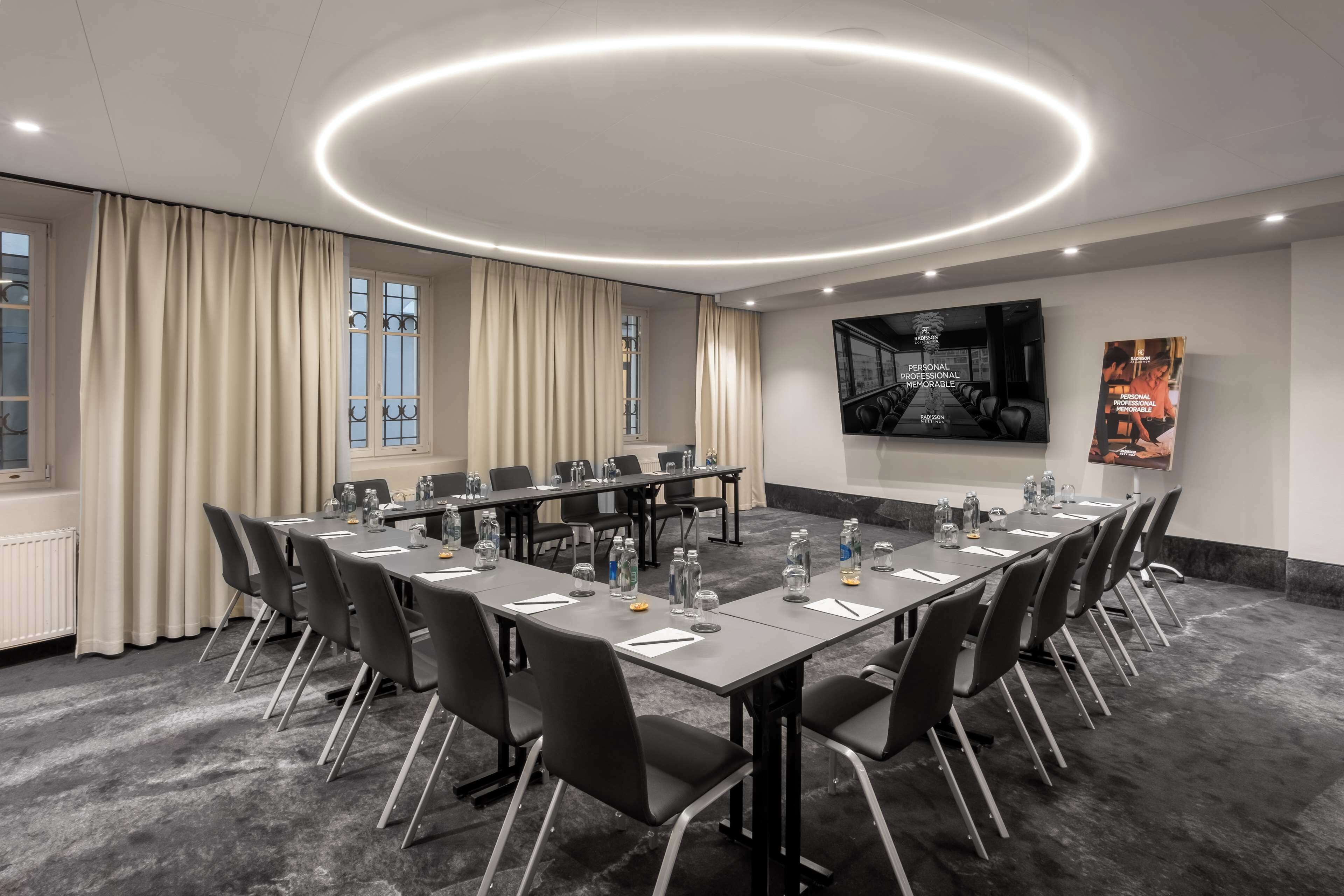 A conference room with a long table, chairs, and a modern ceiling light fixture.