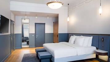 Una habitación de hotel moderna con una cama grande, televisión, armario de madera y una mesita de noche pequeña.