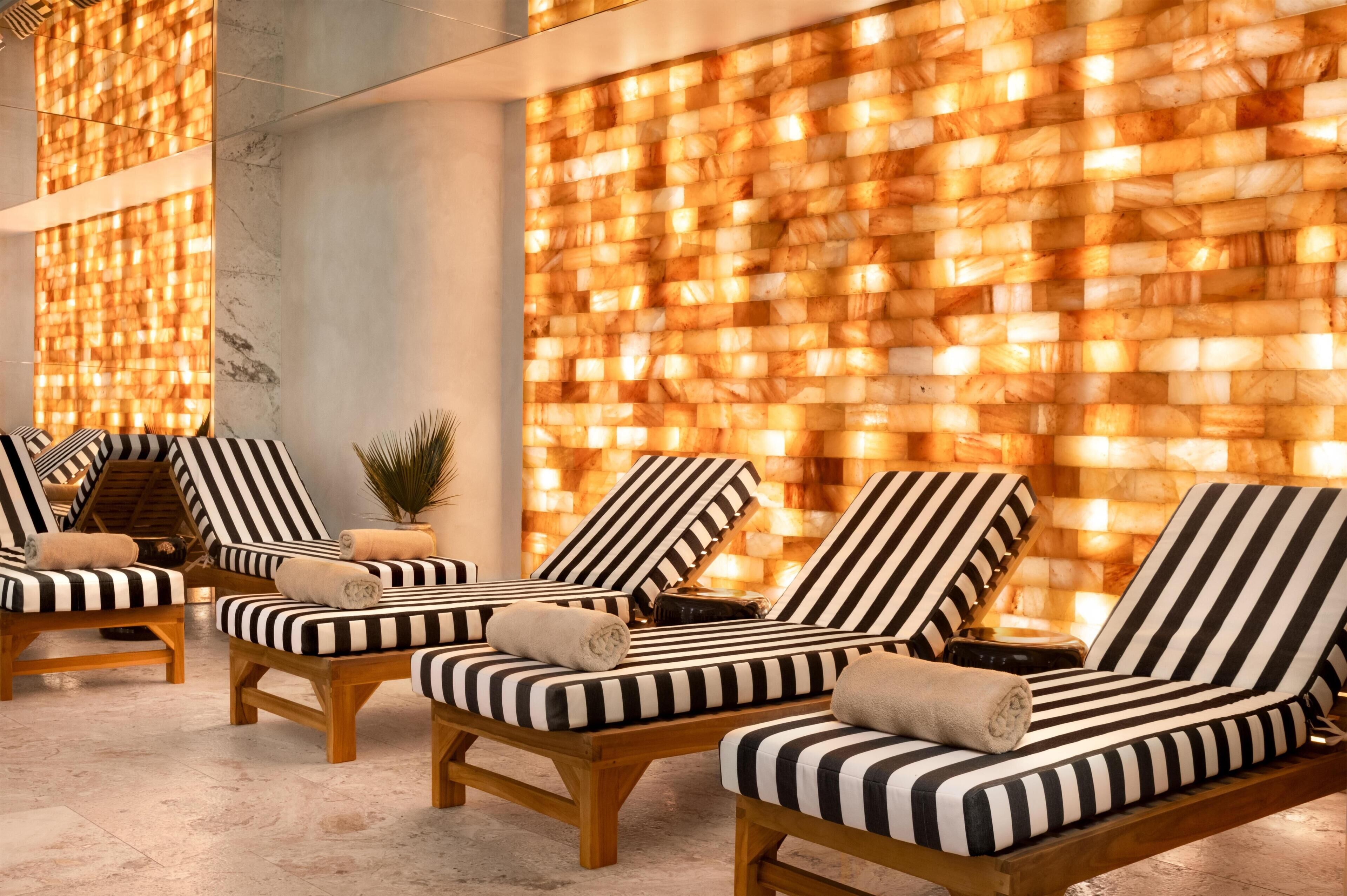 Un espacio de spa con sillones reclinables a rayas y una pared con textura.