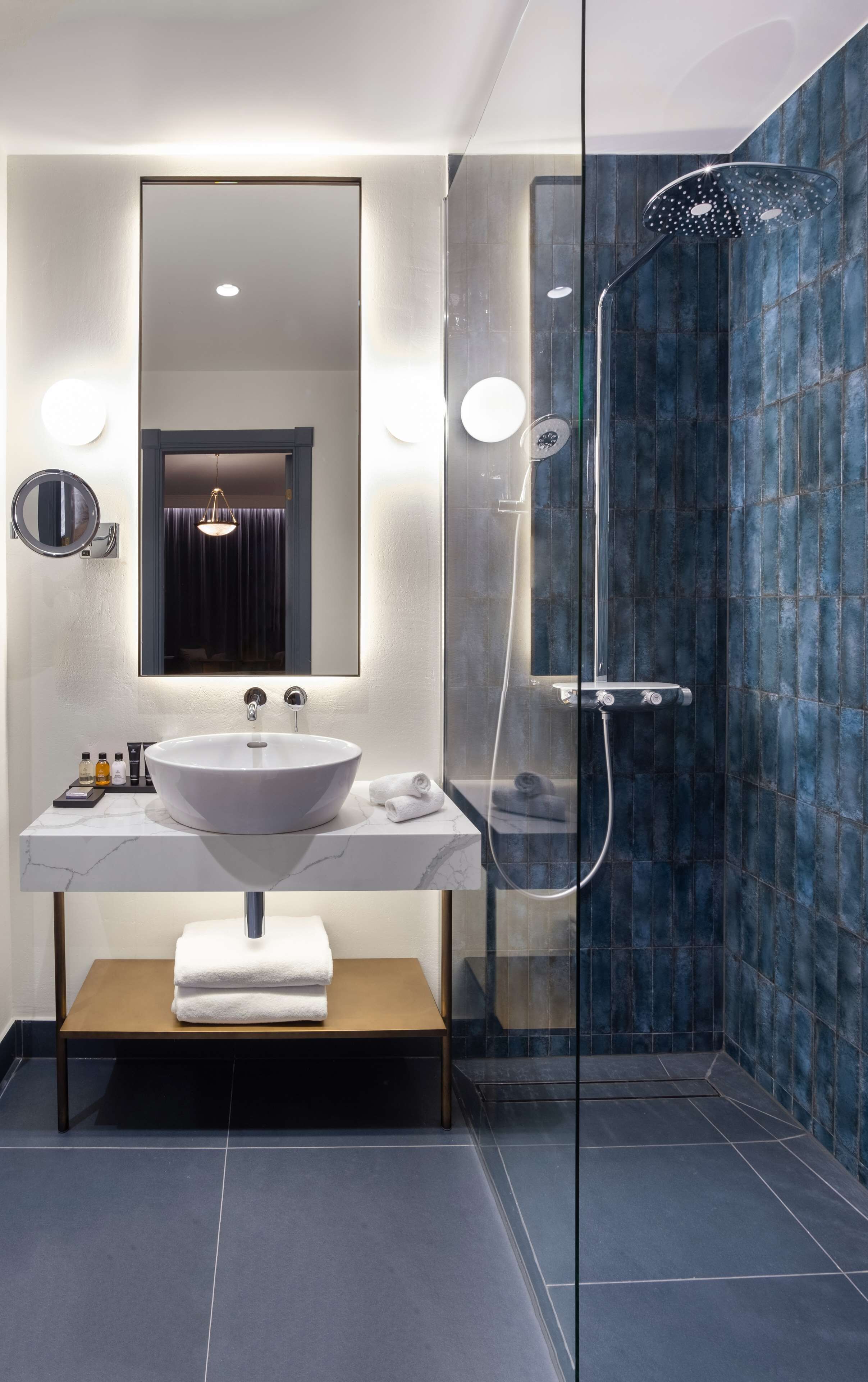 A modern bathroom with a large white sink, a mirror, and a glass-enclosed shower area.