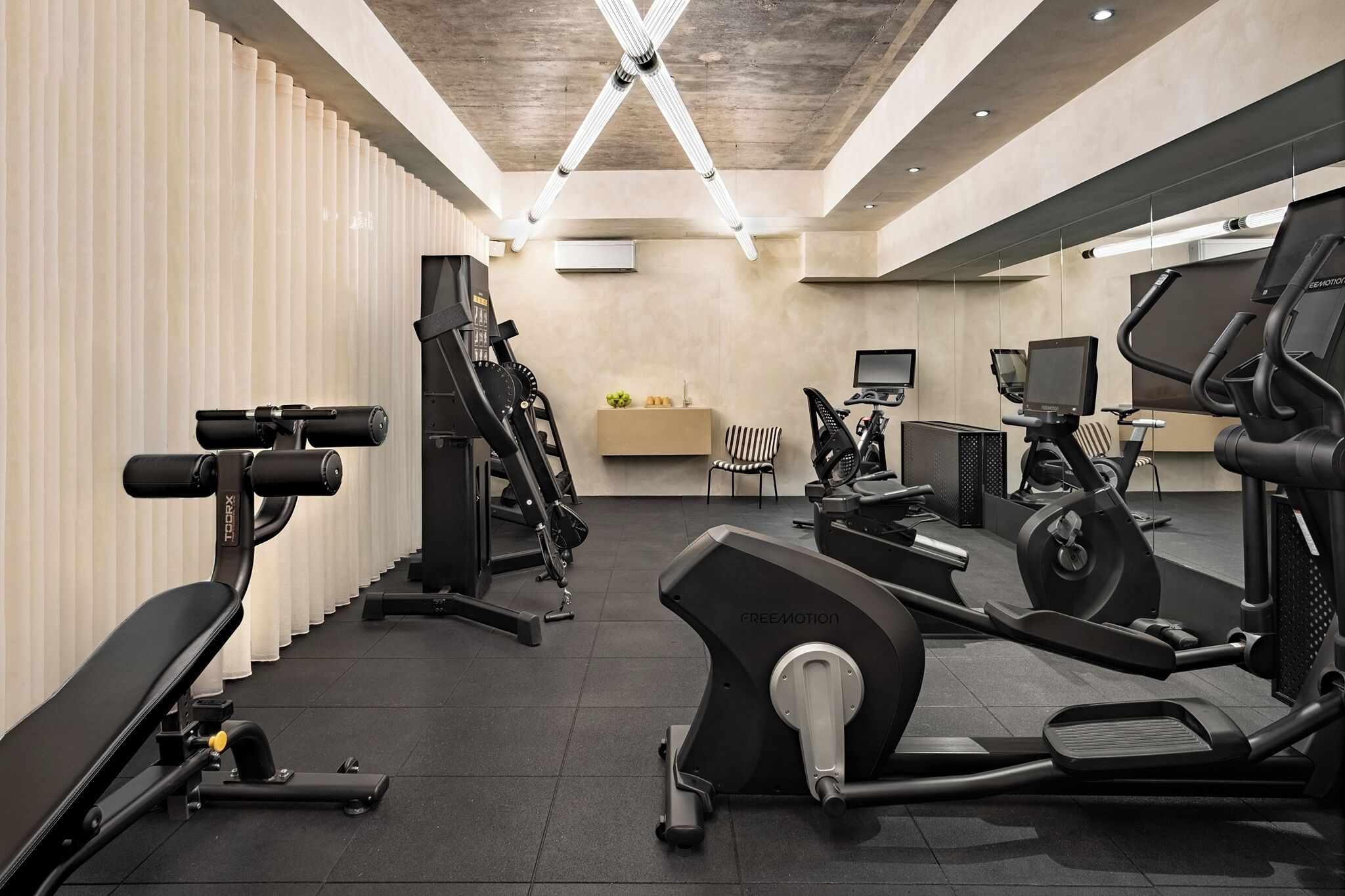 Ett gym med träningsutrustning, en receptionsdisk och en TV som är monterad på väggen.