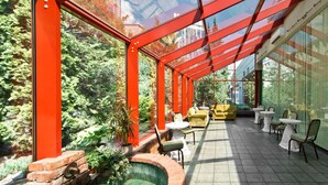 A conservatory with glass walls, a brick fireplace, and outdoor seating. - Best Western Vilnius (Vilnius)