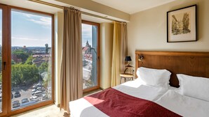 A hotel room with a large bed, a view of a cityscape through a sliding glass door, and a framed picture on the wall. - Best Western Vilnius (Vilnius)