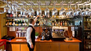 Un espace bar avec de nombreux verres à vin suspendus au-dessus d’étagères remplies de différentes bouteilles.