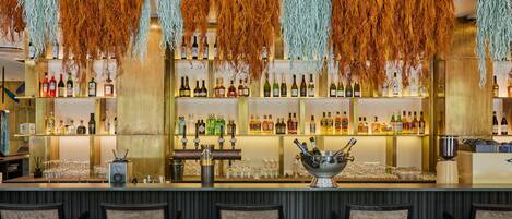 A bar area with multiple shelves of liquor bottles, a bar counter, and several chairs.