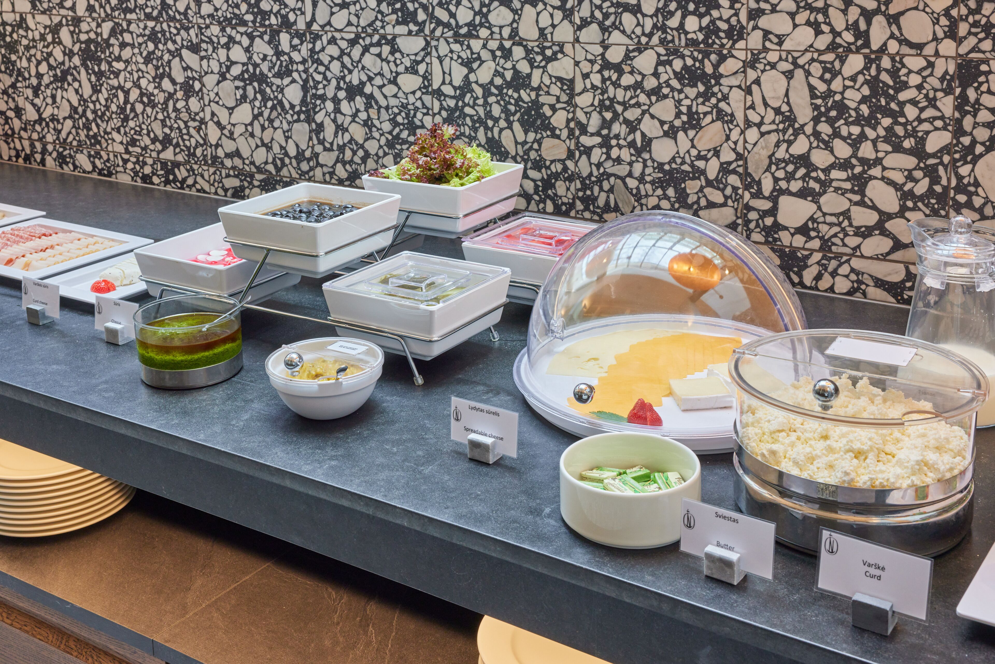 A buffet counter with various food items and labels.