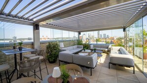 A rooftop terrace with a glass roof, outdoor seating, and a city view. - Neringa Hotel (Vilnius)