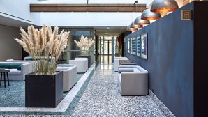 A modern lobby with a glass entrance, seating areas, and contemporary lighting fixtures. - Neringa Hotel (Vilnius)