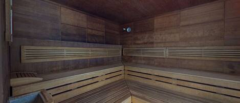 A sauna with wooden benches and a sloped floor.