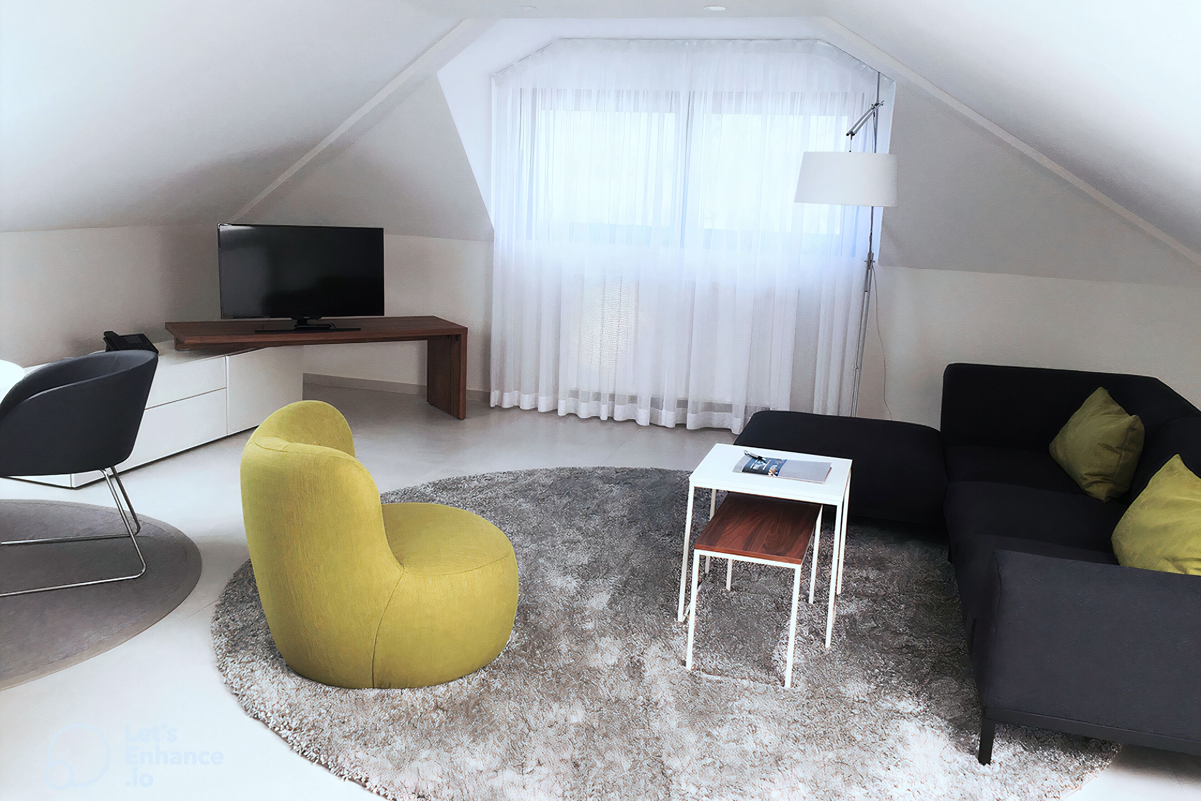 A modern living room with a flat-screen TV, a yellow armchair, a black sofa with green cushions, and a white coffee table.