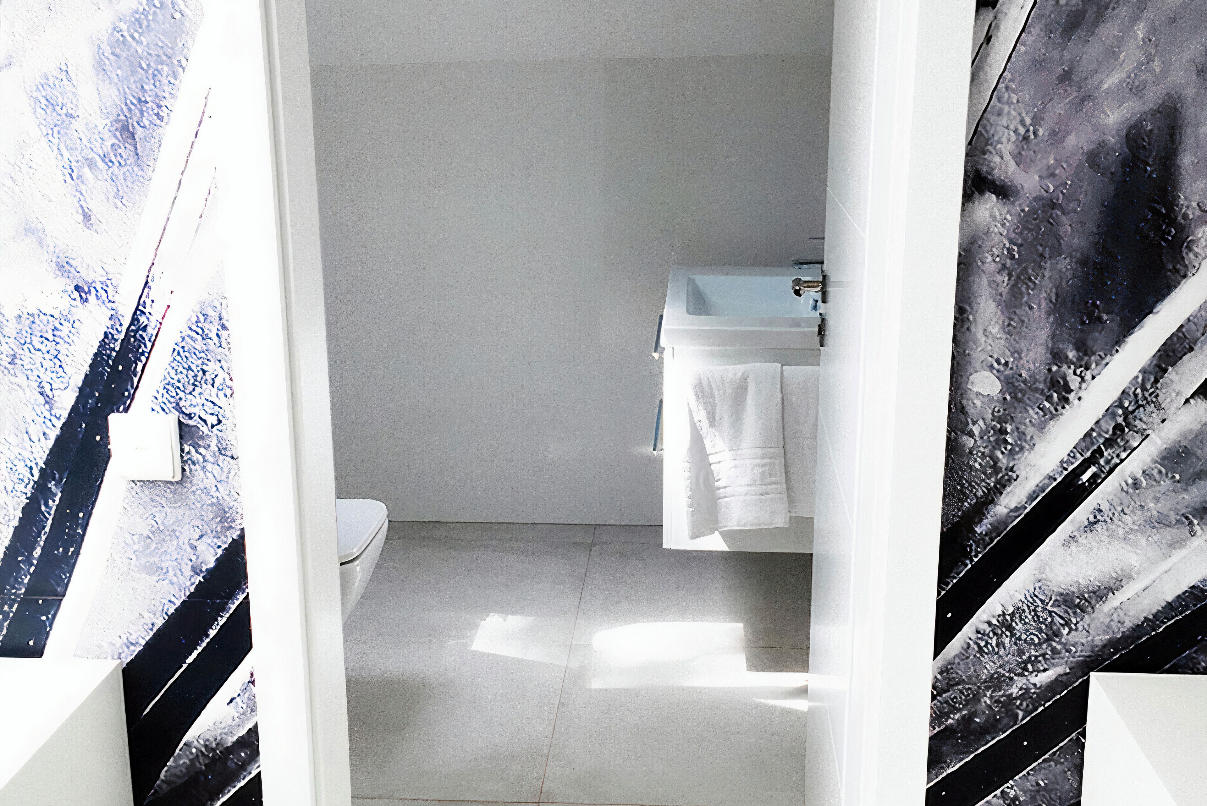 A bathroom with a white toilet, a sink, and a towel hanging on the wall.