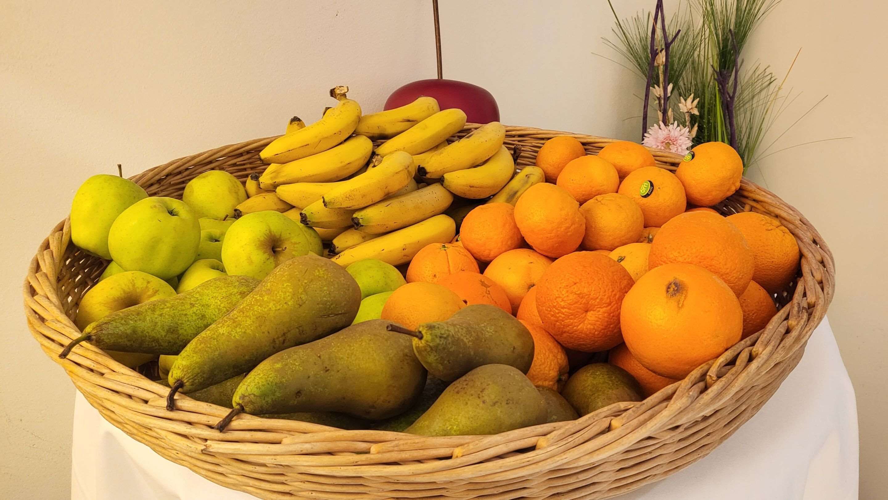 A wicker basket filled with various fruits including bananas, apples, pears, and oranges.