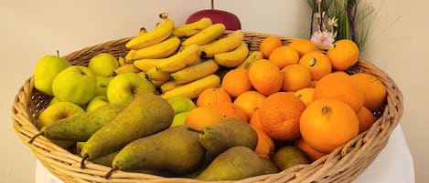 Een rieten mand gevuld met diverse soorten fruit, zoals bananen, appels, peren en sinaasappels.