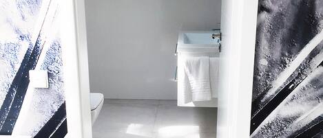 A modern bathroom with a white sink, a toilet, and a shower area.