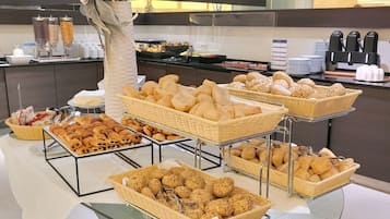 A buffet with various bread and pastries displayed in wicker baskets.