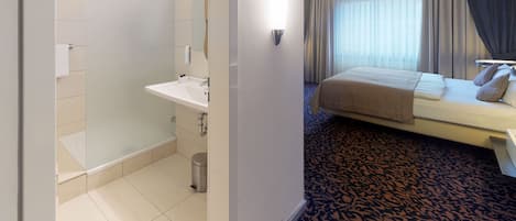 Habitación de hotel con baño, cama y alfombra estampada.