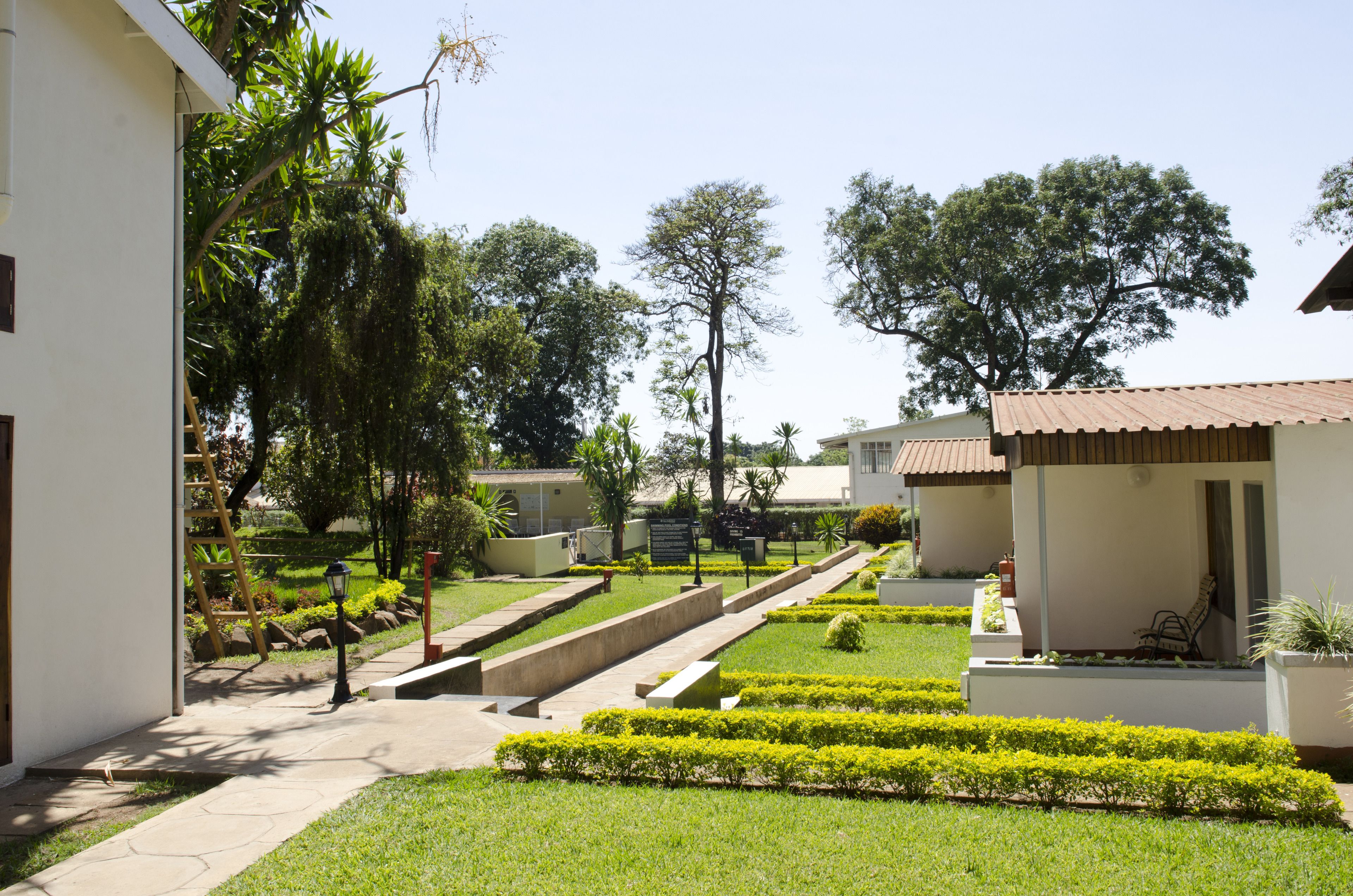 Un jardin bien entretenu, agrémenté de sentiers, de haies taillées avec soin et d’une variété d’arbres.