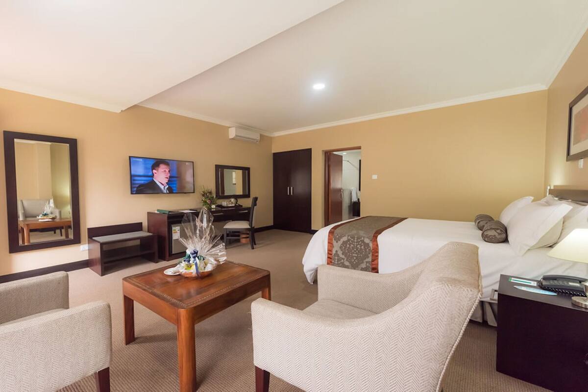 A hotel room with a bed, two armchairs, a coffee table, a TV, a desk, and a wardrobe.